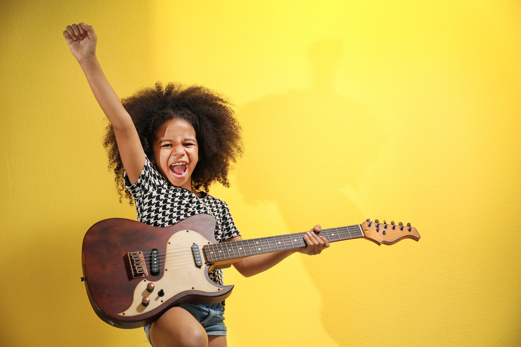 Little Girl Playing Guitar on Yellow Background